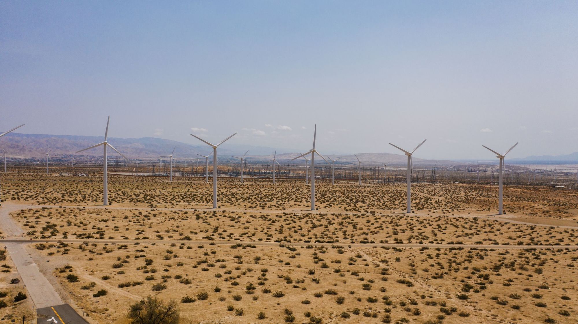 Rows of wind turbines on a flat desert plain under a clear sky